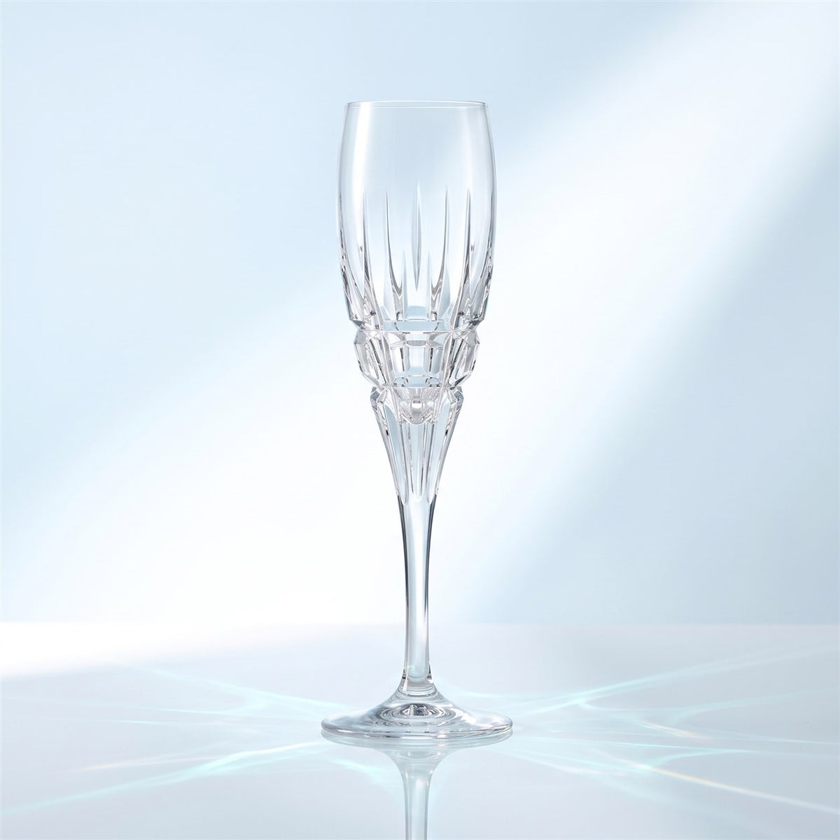 Flûte à champagne RCR Carrara 16 cl, vide, à facettes taillées à la base du bol, sur une surface blanche brillante