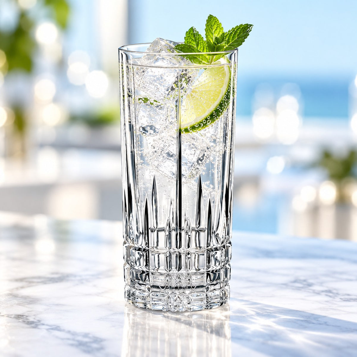 Verre long drink Spiegelau Perfect Serve rempli d'un cocktail à la menthe, au citron vert et aux glaçons sur un comptoir en marbre
