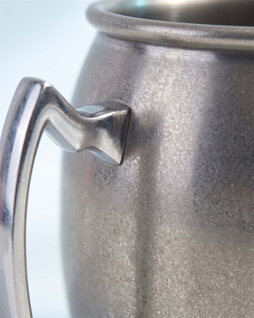 Gros plan sur la finition argent vieillie du mug et le bord de la poignée