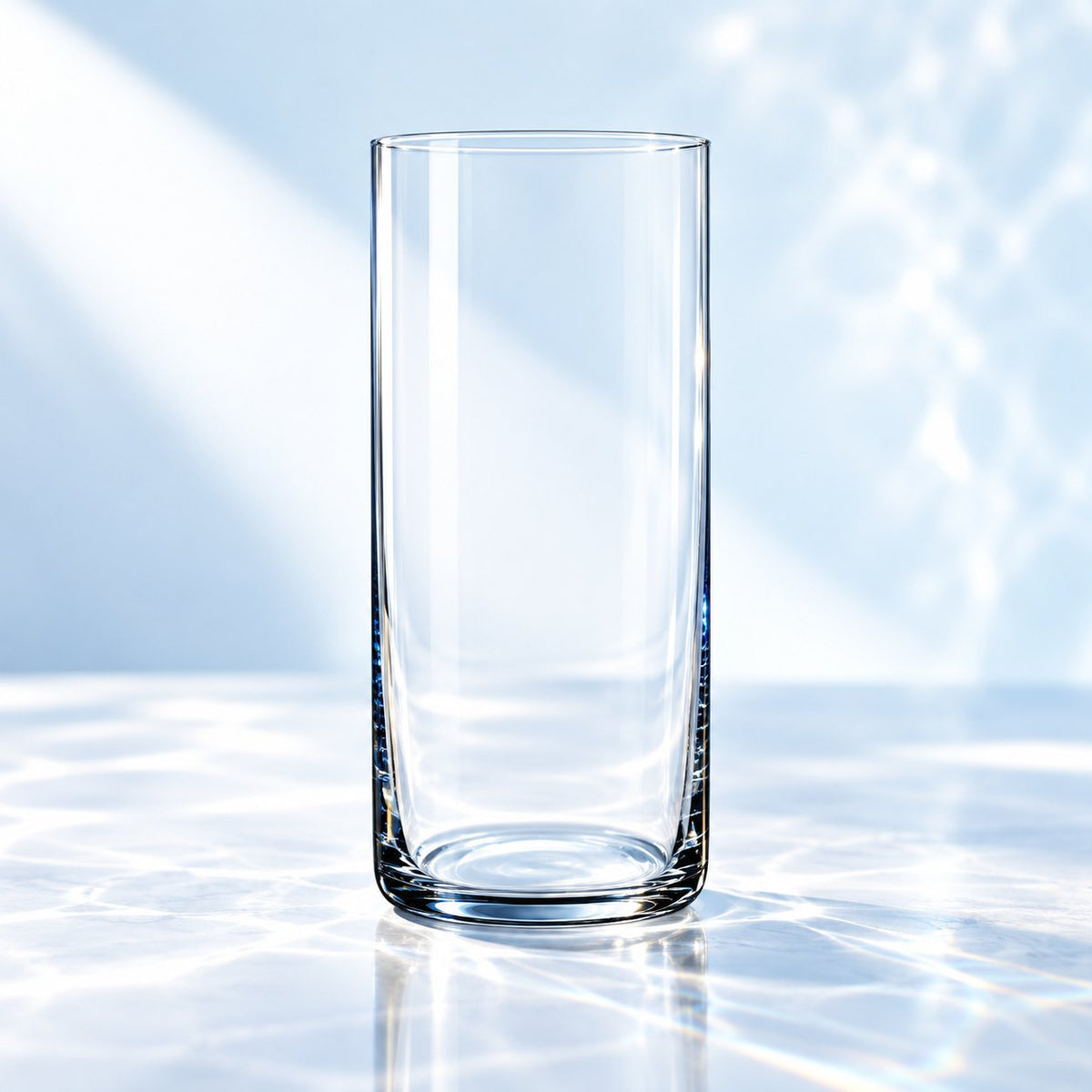 Verre long drink Nude Finesse 35 cl, forme cylindrique, vu de face sur un plan de marbre lumineux