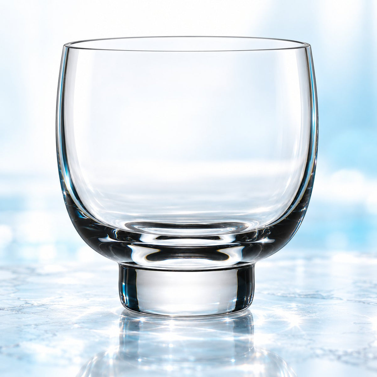 Verre à whisky Nude Malt 25 cl à base surélevée, vu de face sur un plan de marbre lumineux