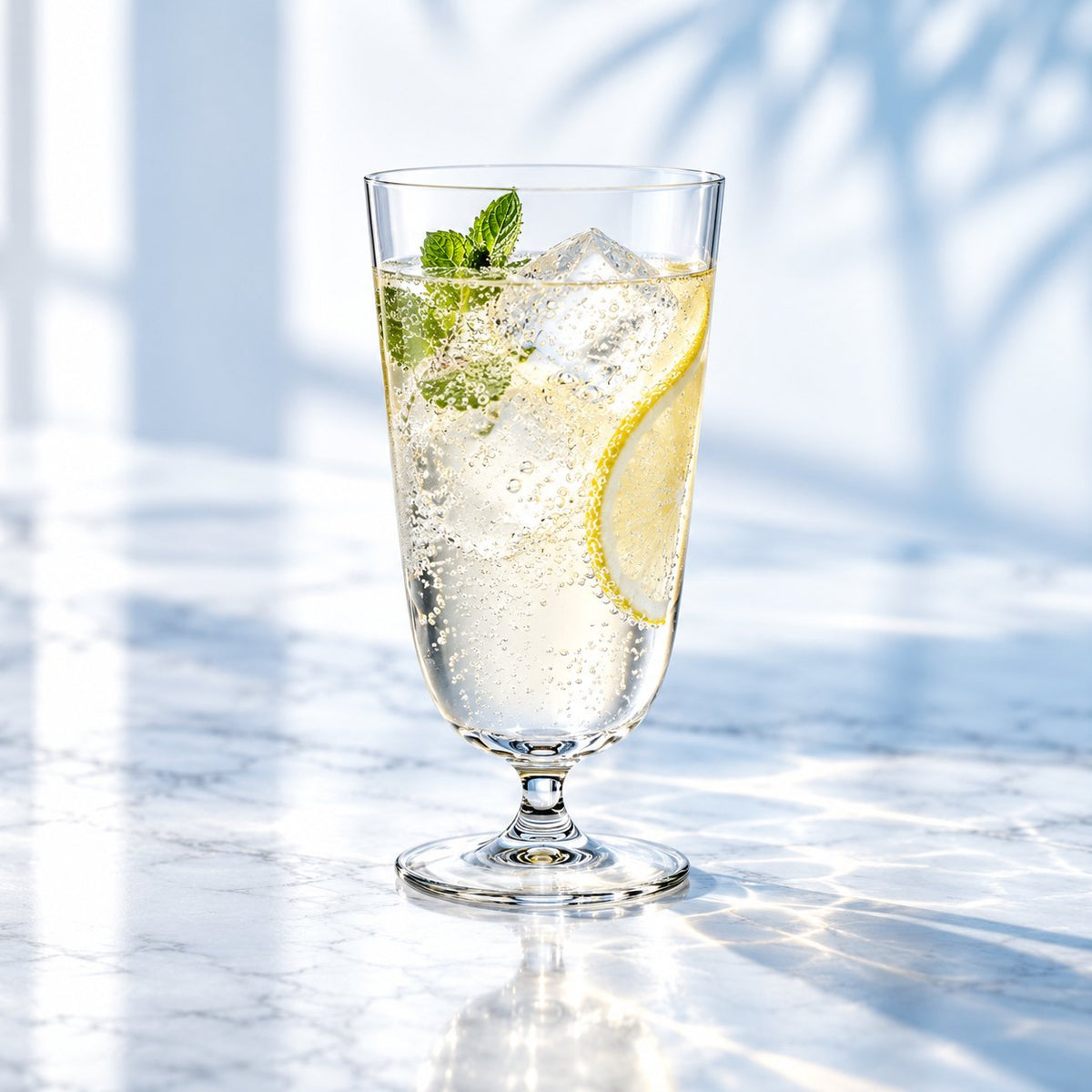 Verre Nude Bar Giani rempli d'un cocktail pétillant avec citron et menthe sur un comptoir en marbre
