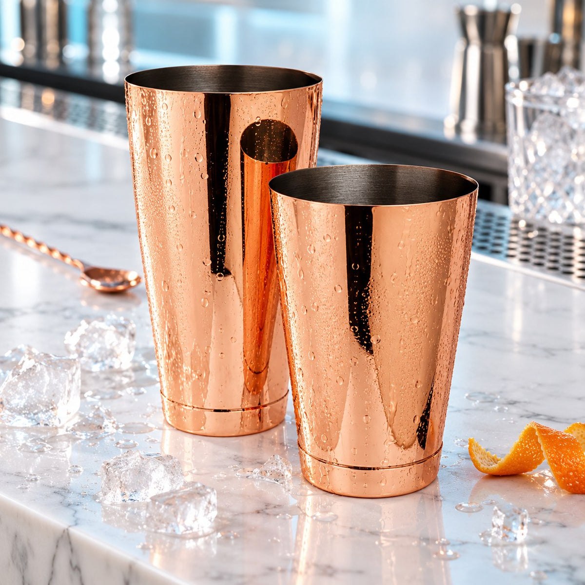 Shaker Boston Mezclar cuivre sur un comptoir en marbre avec glaçons et zeste d'orange