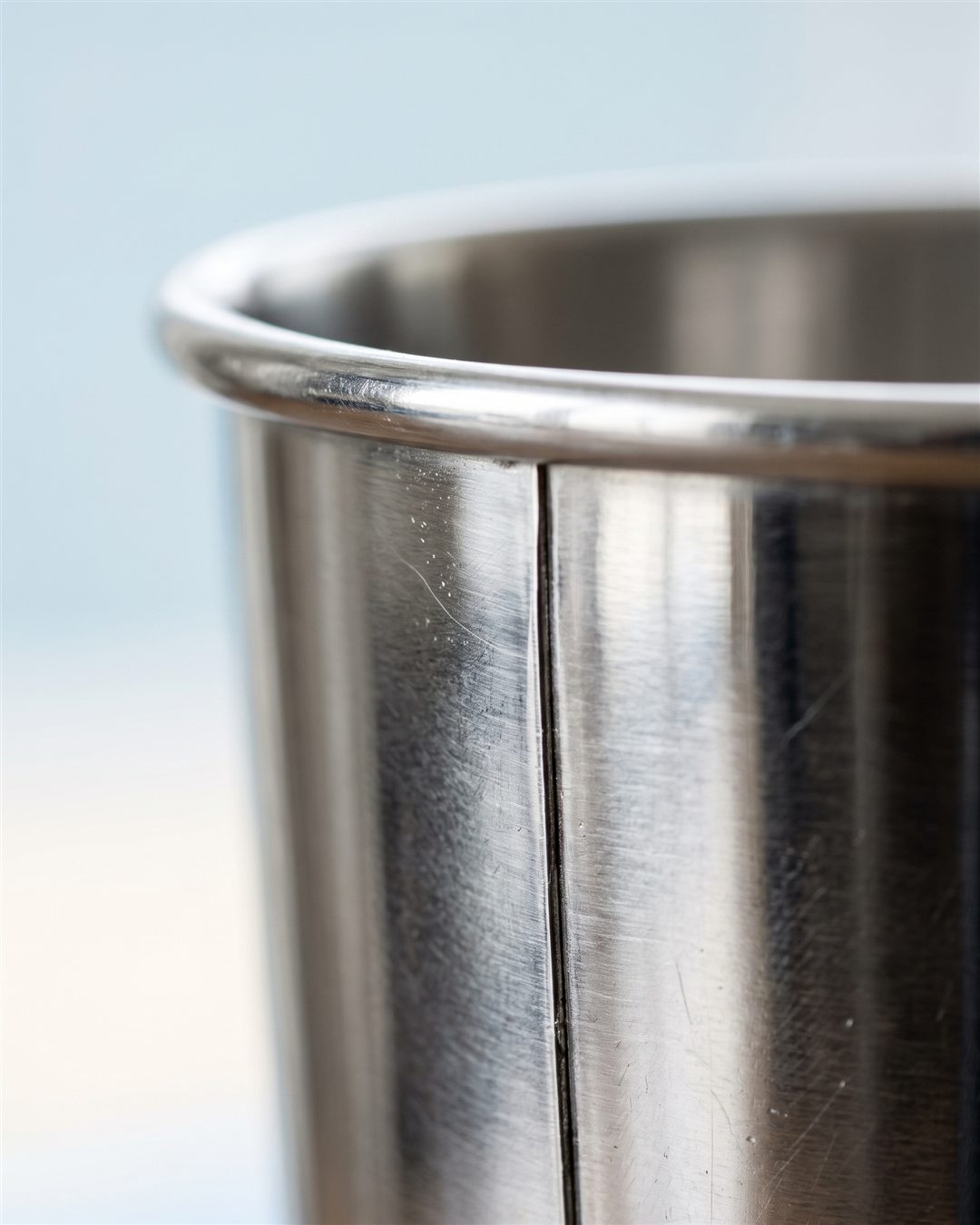 Gros plan sur le bord roulé et la soudure verticale de la tin en inox poli