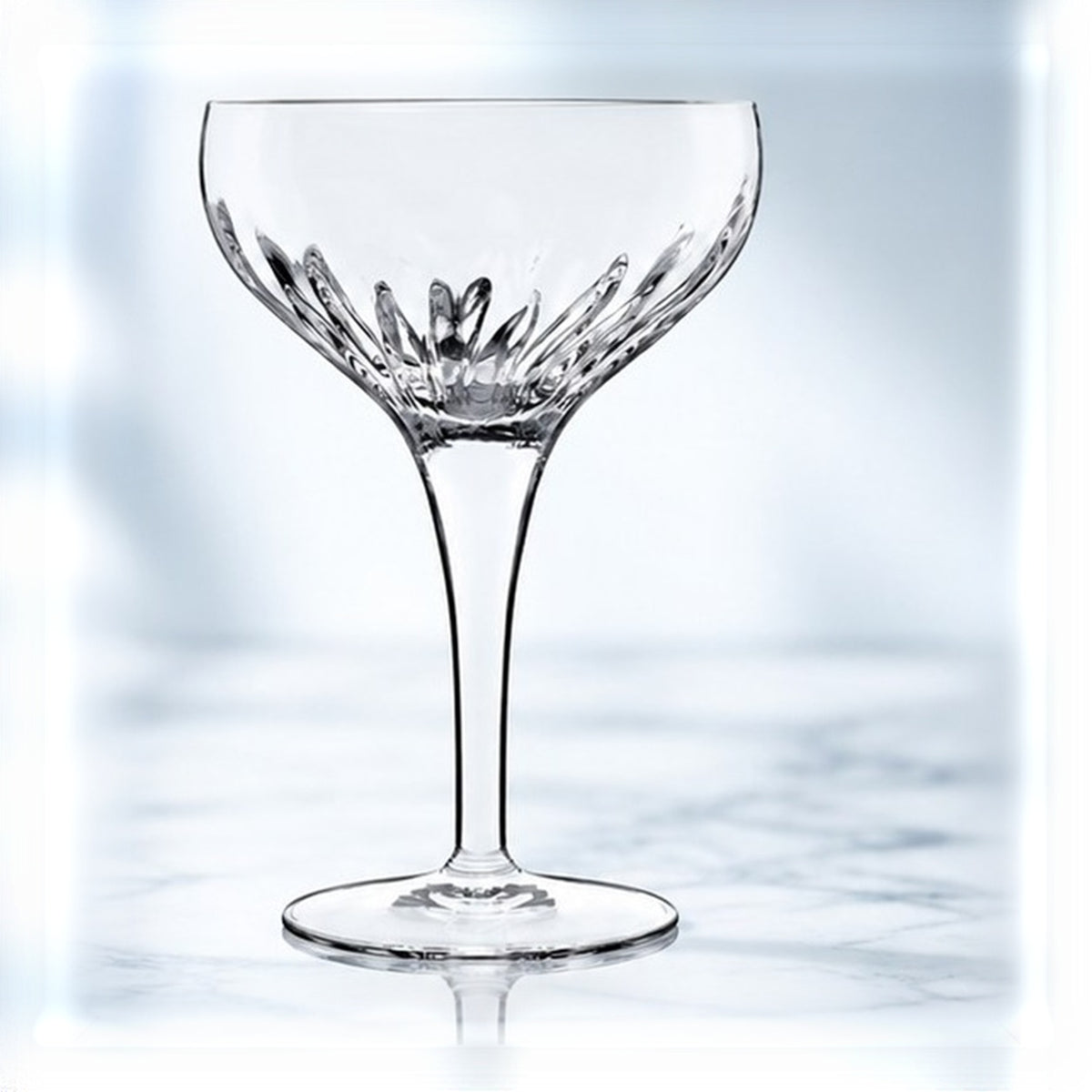 Verre à cocktail Luigi Bormioli Mixology 22 cl, coupe taillée en rayons, vu de face sur un plan de marbre