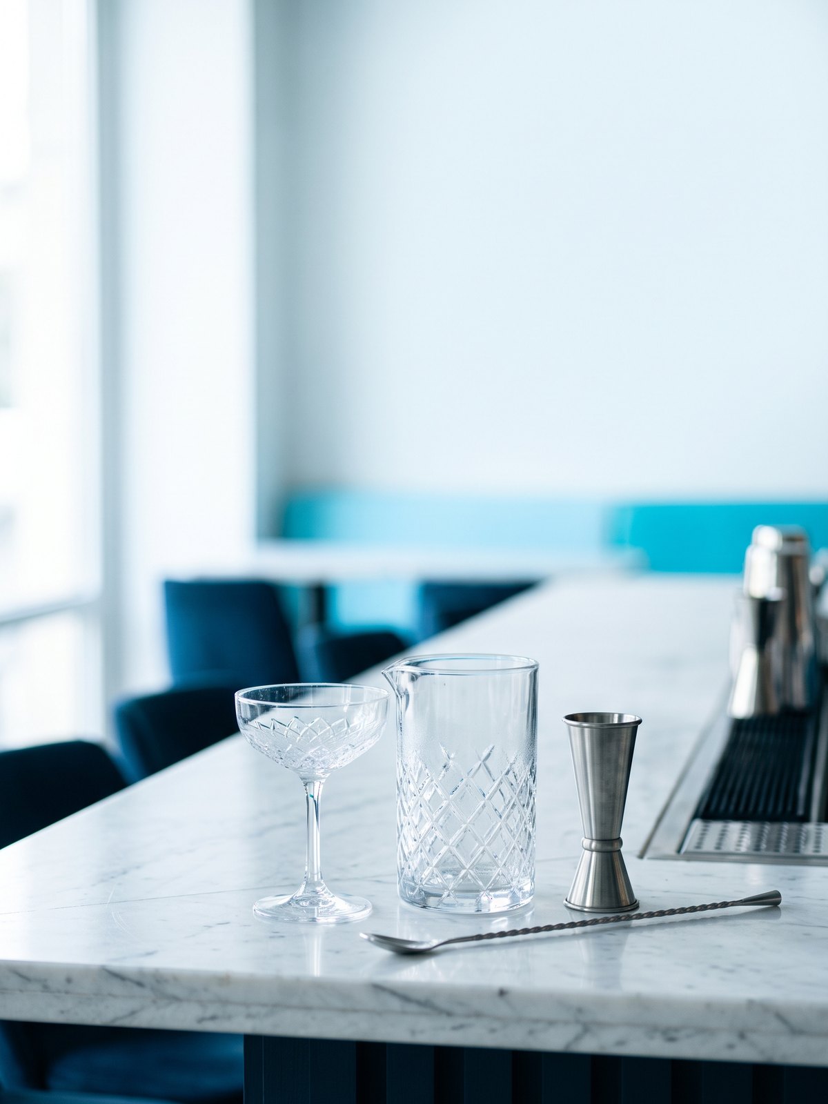 BWA, nouvelle identité : verrerie et matériel de bar professionnel, verre à mélange en cristal, jigger et cuillère de bar sur un comptoir en marbre blanc