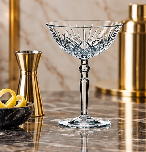 Coupette Nachtmann Palais 20 cl, à côté d'un jigger doré et d'un shaker