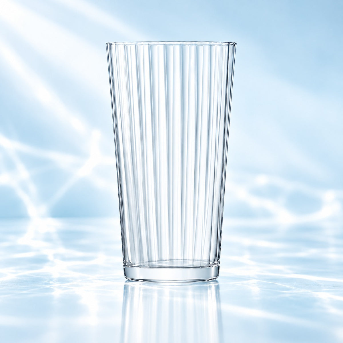 Verre long drink Gio Line 32 cl à côtes verticales, vide, sur une surface lumineuse bleutée