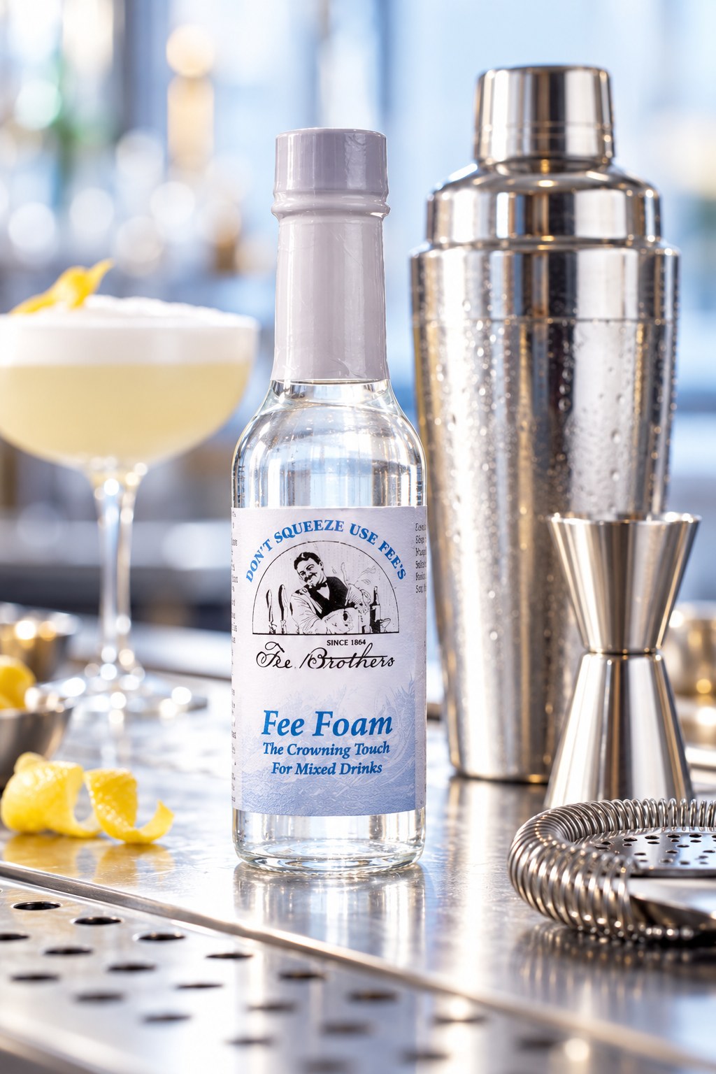 Flacon de Fee Foam près d'un shaker, d'un jigger et d'un cocktail mousseux sur un comptoir de bar