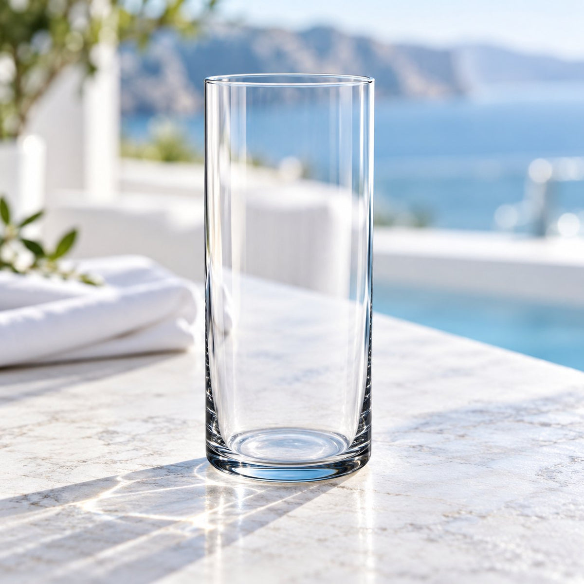 Verre long drink Nude Finesse vide sur un comptoir en marbre, vue sur la mer