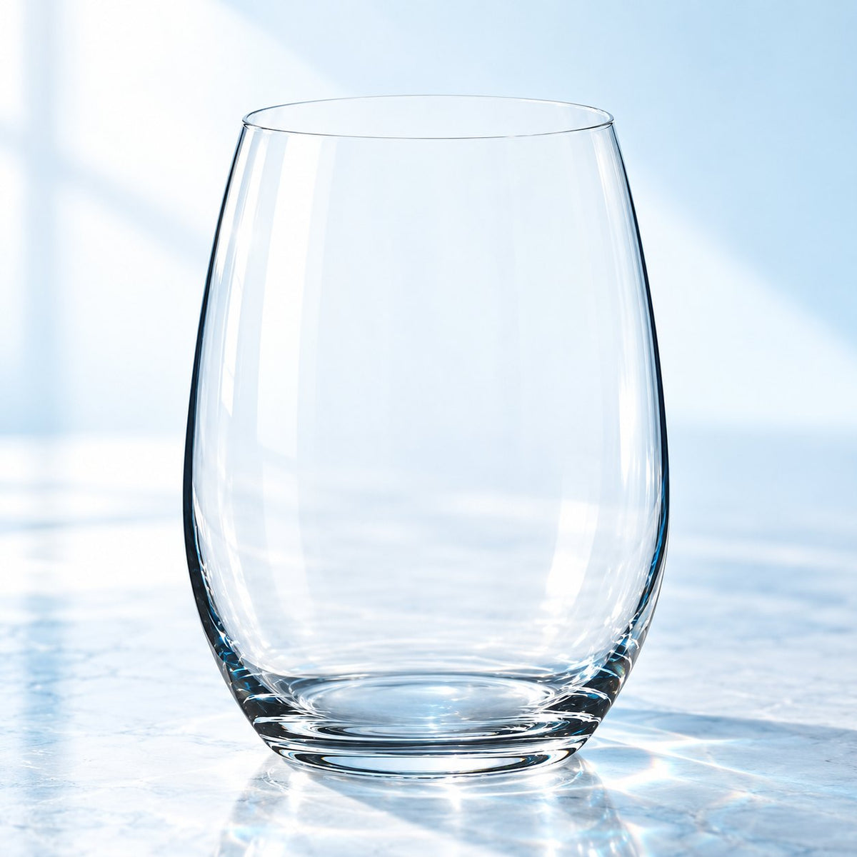 Verre à eau Nude Pure 61 cl sans pied, vu de face sur un plan de marbre lumineux