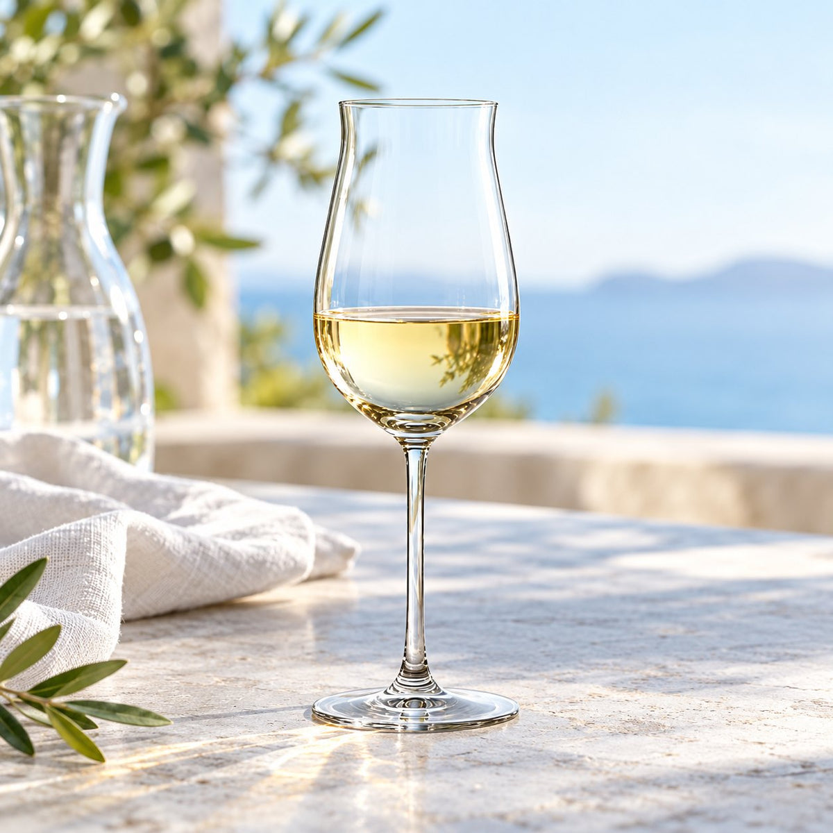 Verre à vin Nude Vintage rempli de vin blanc sur une table, vue sur la mer