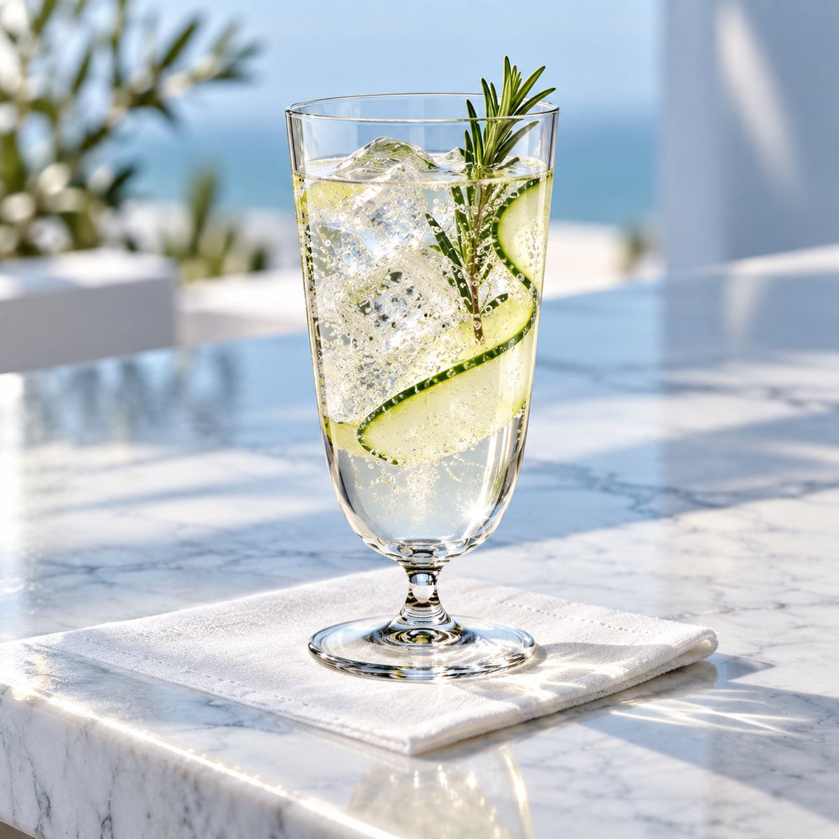 Verre Nude Bar Giani rempli d'un cocktail au romarin, concombre et citron, posé sur une serviette