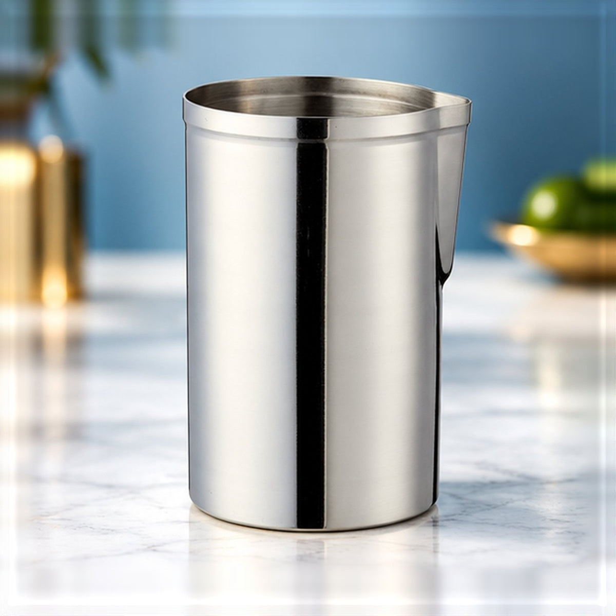 Verre à mélange Mr Slim en inox argent avec bec verseur, vu de face sur un plan de marbre