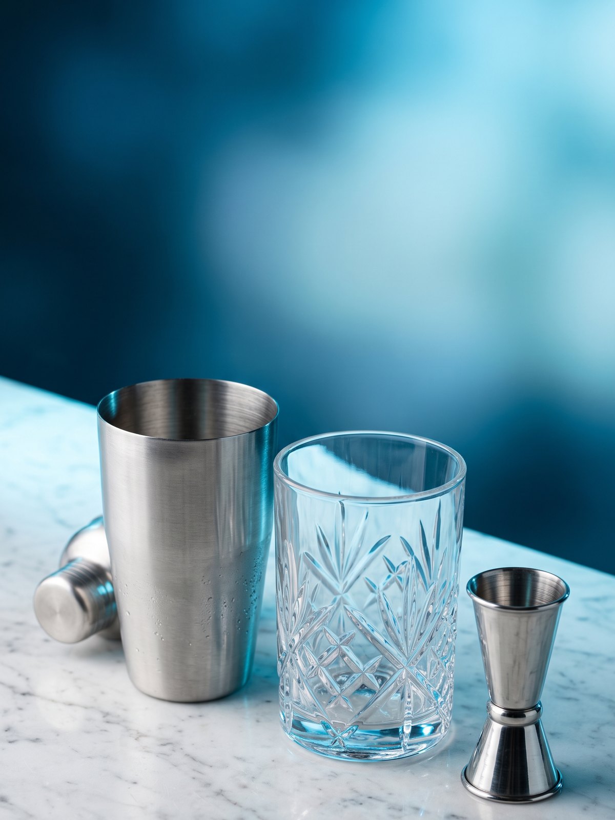 BWA, matériel de bar de qualité professionnelle : shaker Boston en inox et verre à mélange en cristal taillé sur un plan de marbre, avec jiggers